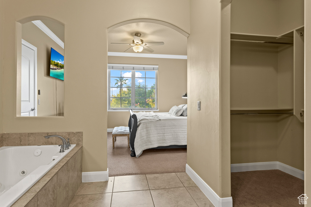 Bathroom featuring ornamental molding, ceiling fan, tile patterned floors, and a relaxing tiled tub