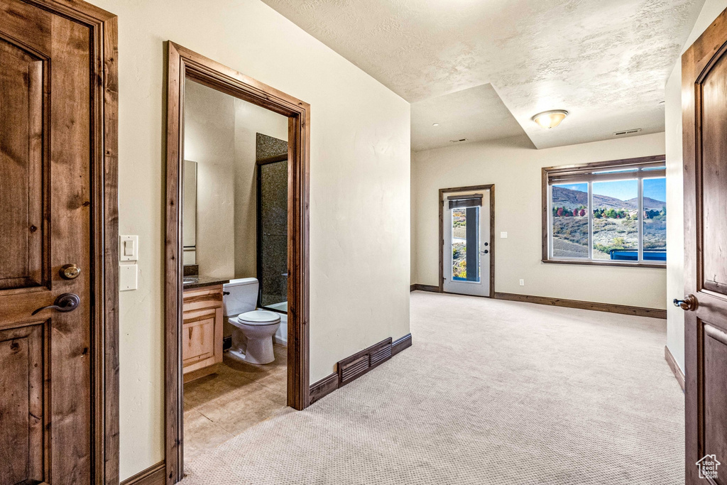 Corridor featuring light colored carpet and a textured ceiling