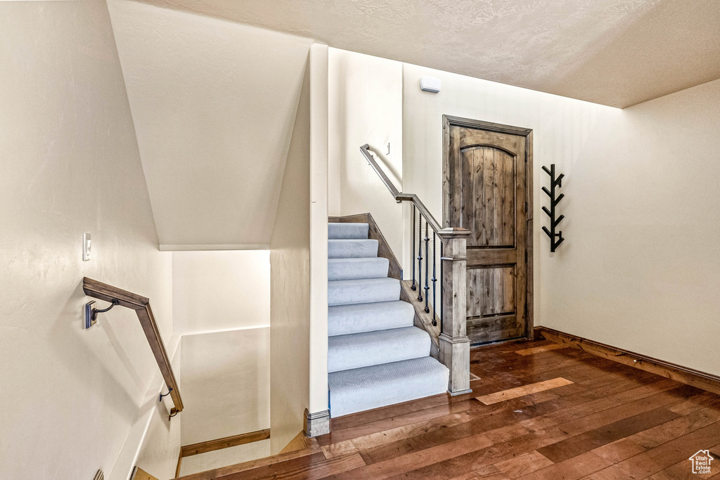 Stairs featuring a textured ceiling and wood-type flooring