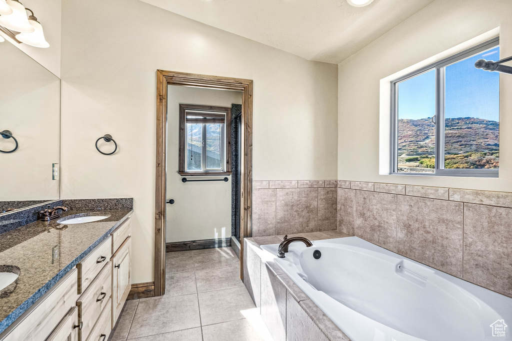 Bathroom featuring independent shower and bath, tile patterned flooring, vanity, and vaulted ceiling