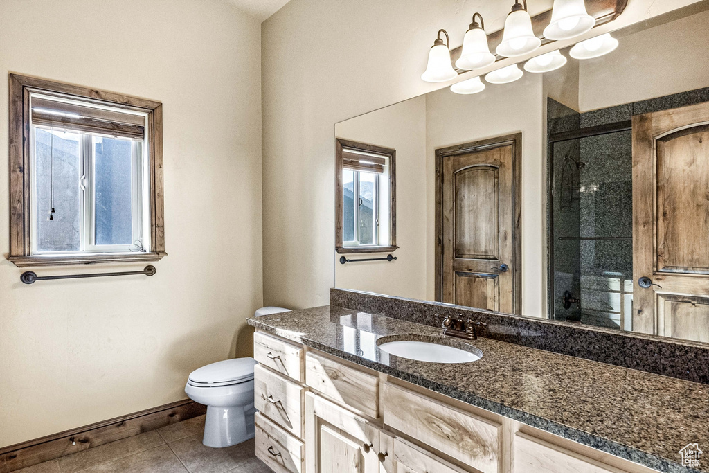 Bathroom with vanity, toilet, an enclosed shower, and tile patterned floors