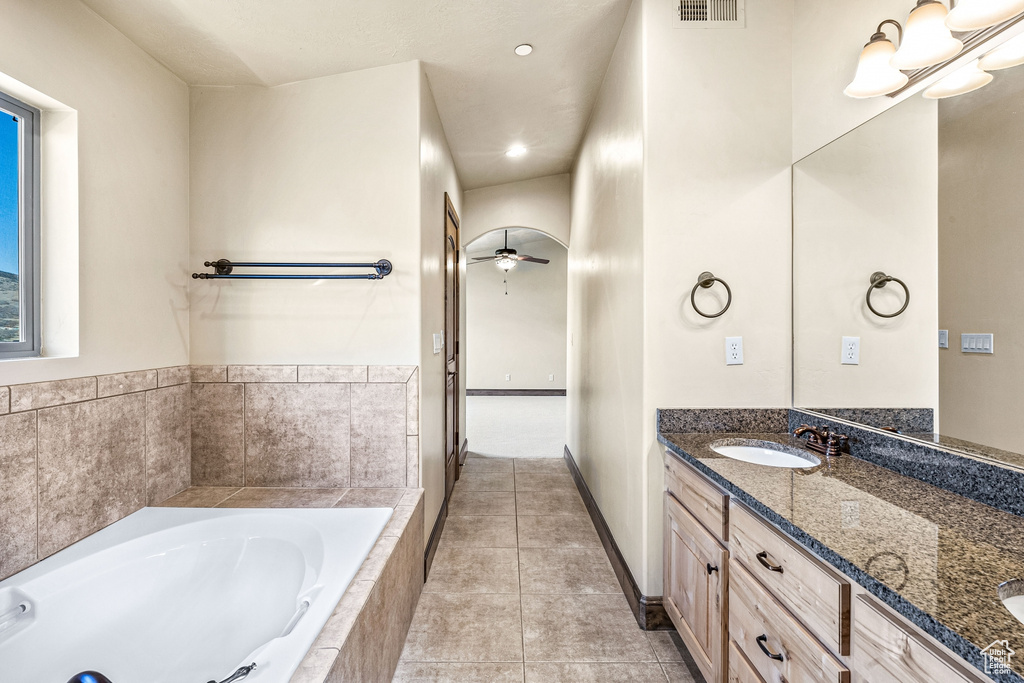 Bathroom featuring tile patterned floors, ceiling fan, tiled bath, and vanity