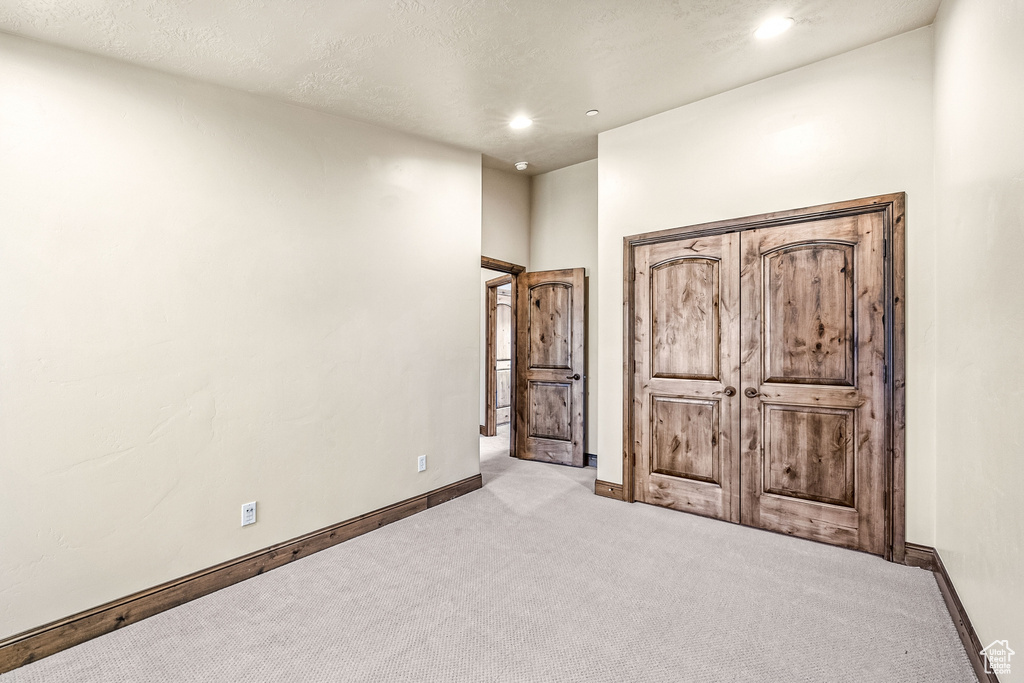 Unfurnished bedroom with a textured ceiling and light colored carpet