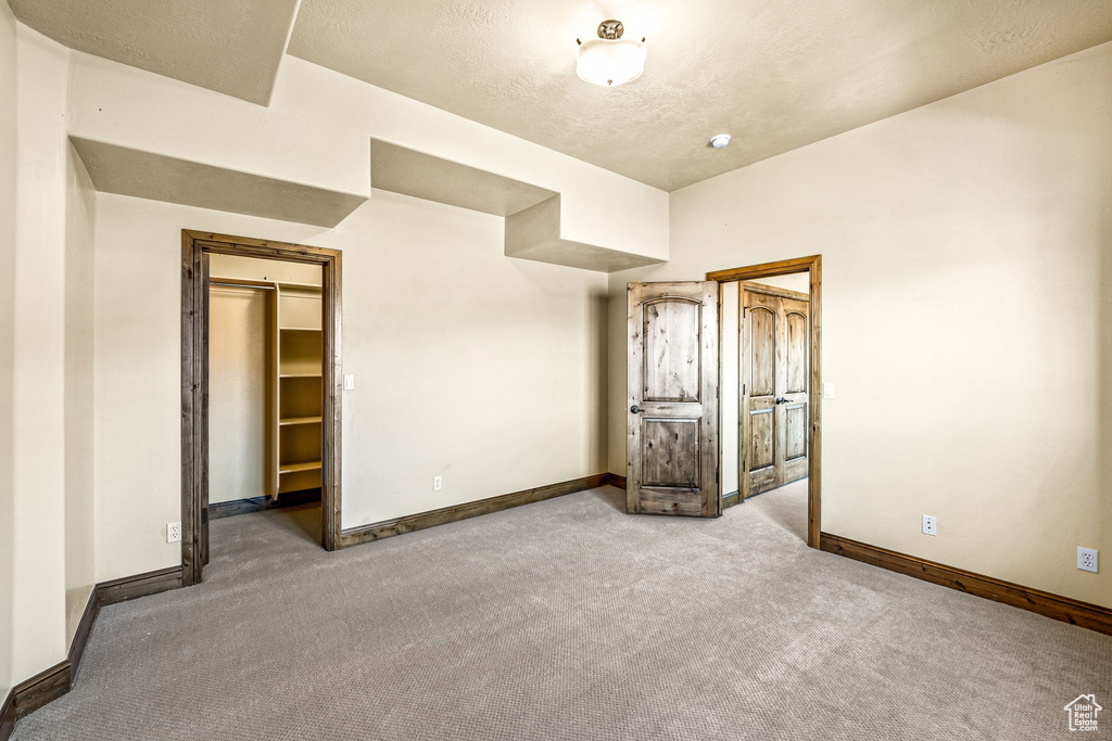 Unfurnished bedroom with a textured ceiling, a closet, carpet flooring, and a spacious closet