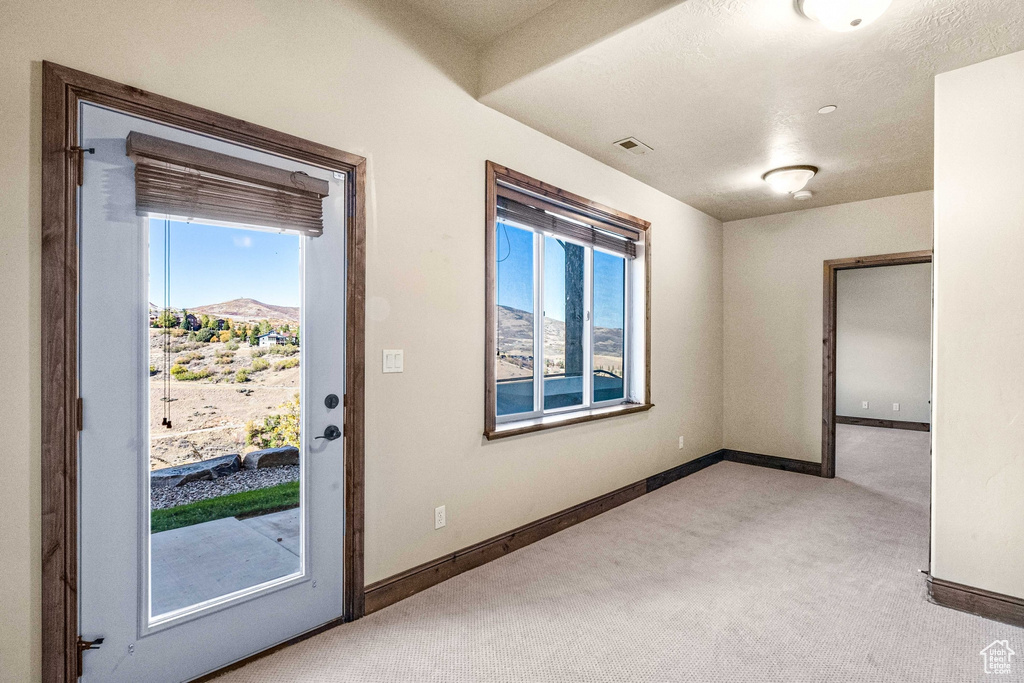 Interior space featuring light colored carpet, plenty of natural light, and a mountain view