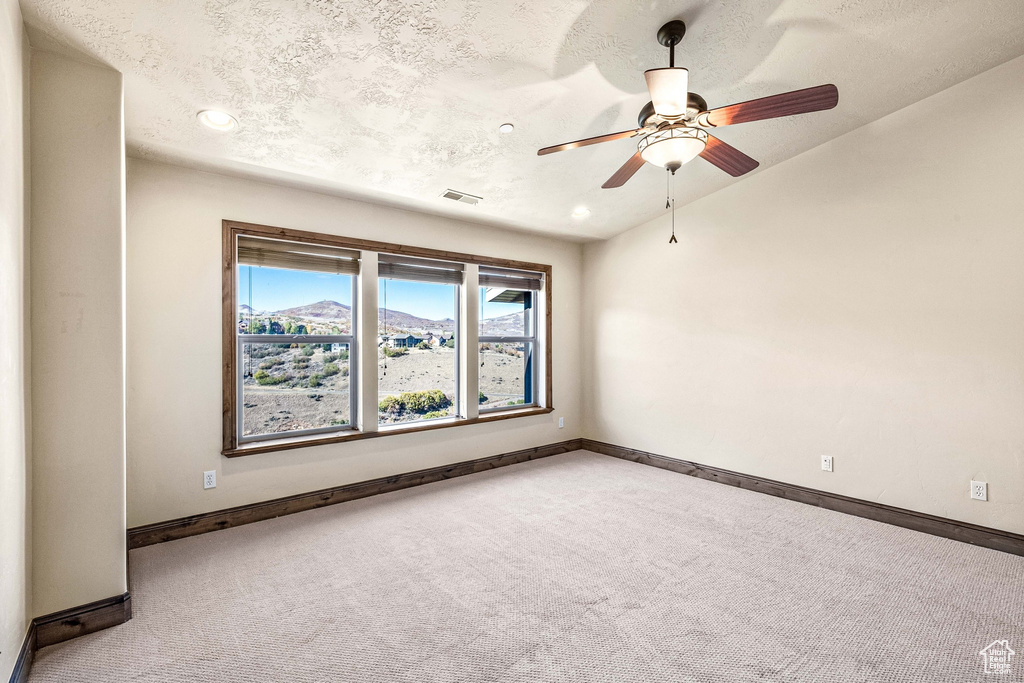 Spare room with a textured ceiling, carpet flooring, ceiling fan, and a mountain view