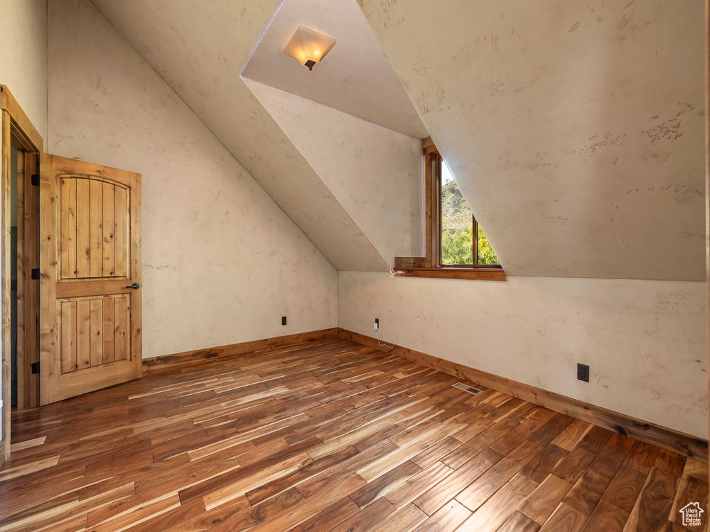 Bonus room with dark hardwood / wood-style floors and vaulted ceiling