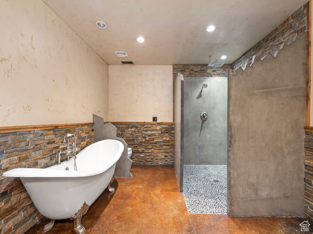 Bathroom with concrete flooring and shower with separate bathtub