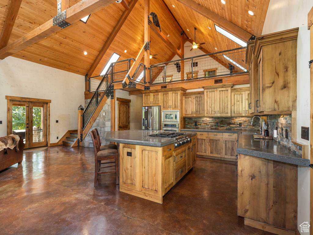 Kitchen featuring a skylight, a kitchen island, high vaulted ceiling, and ceiling fan