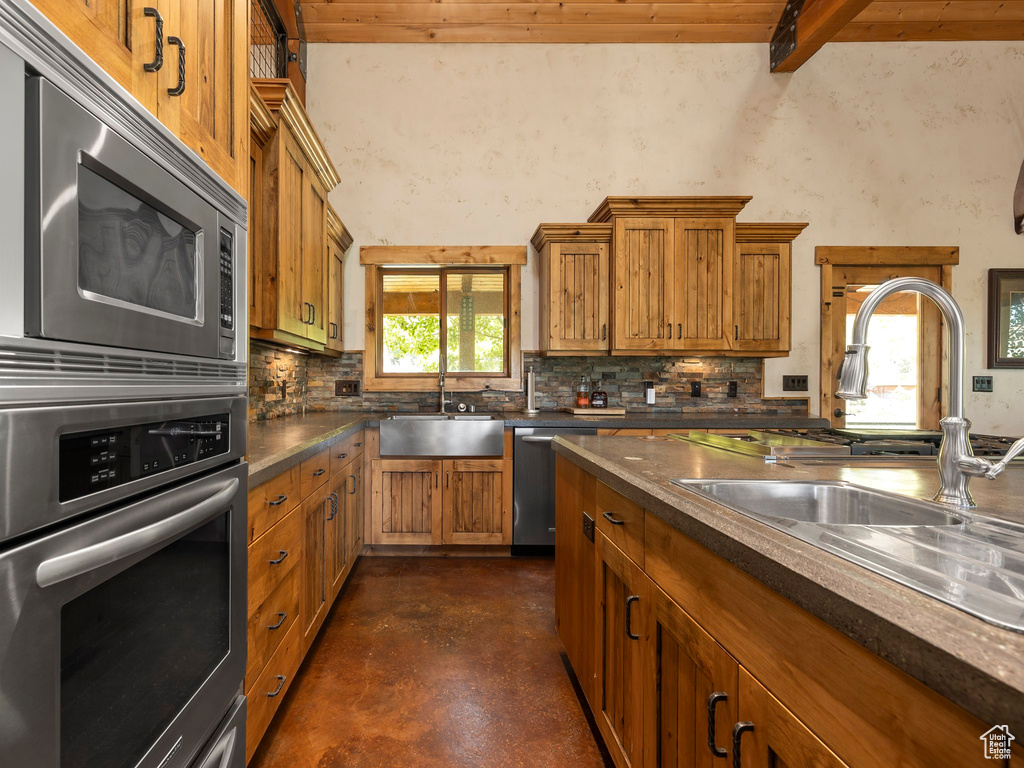 Kitchen featuring beamed ceiling, wood ceiling, stainless steel appliances, sink, and backsplash