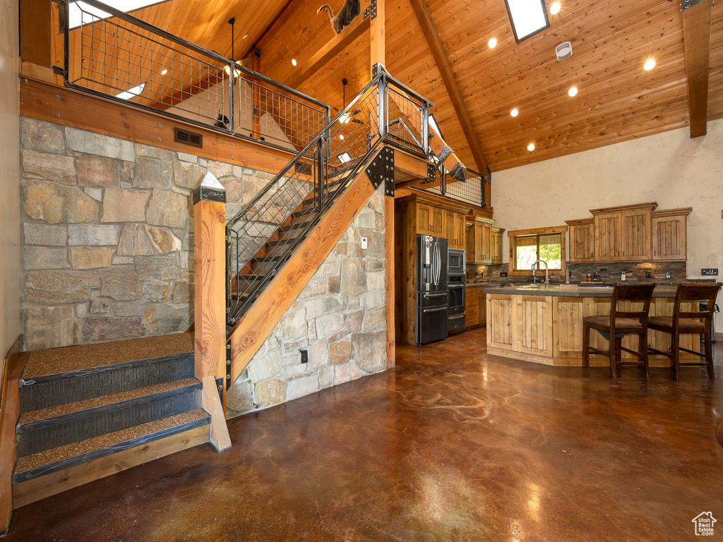 Kitchen with wood ceiling, sink, high vaulted ceiling, a kitchen breakfast bar, and appliances with stainless steel finishes