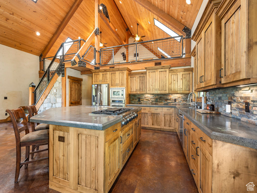 Kitchen with a skylight, high vaulted ceiling, a center island, and stainless steel appliances