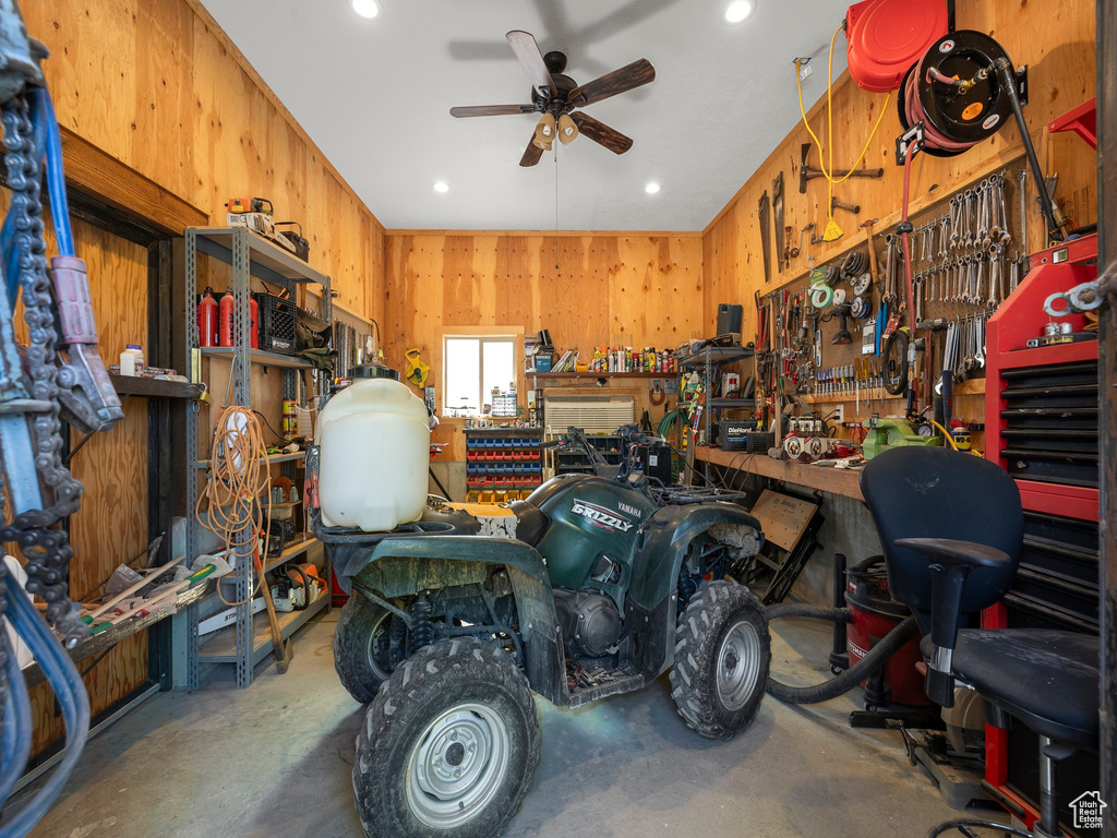 Garage with ceiling fan, wood walls, and a workshop area