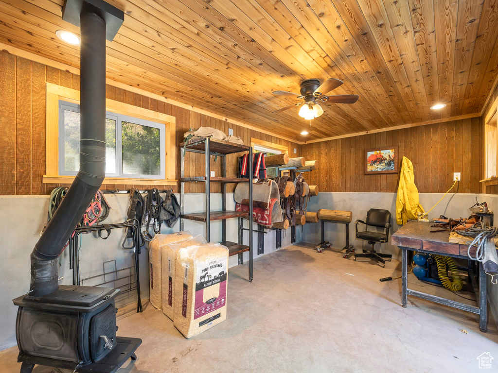 Miscellaneous room with wood walls, ceiling fan, wood ceiling, and a wood stove