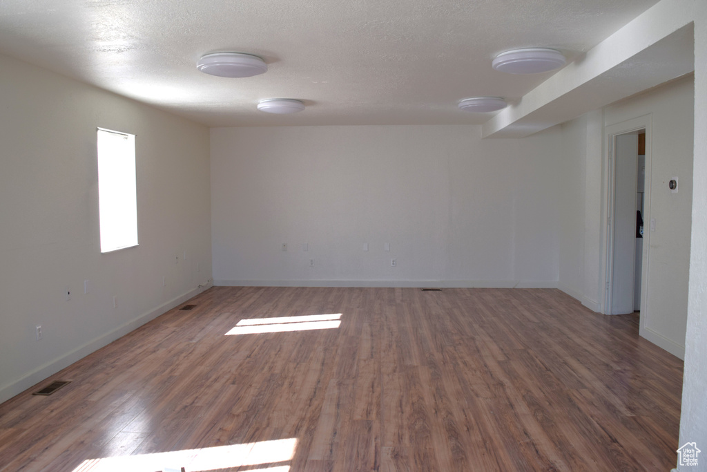 Empty room with a textured ceiling and dark wood-type flooring