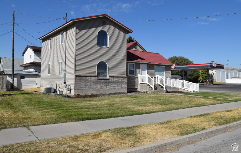 View of front of home featuring cooling unit and a front lawn