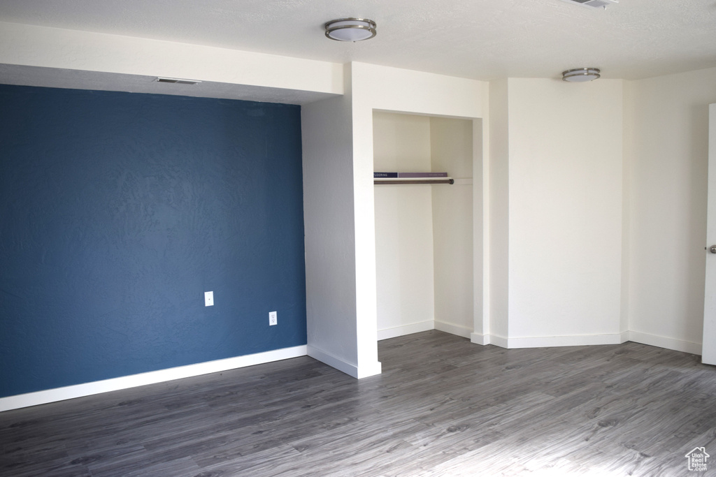 Unfurnished bedroom featuring a closet and dark hardwood / wood-style flooring