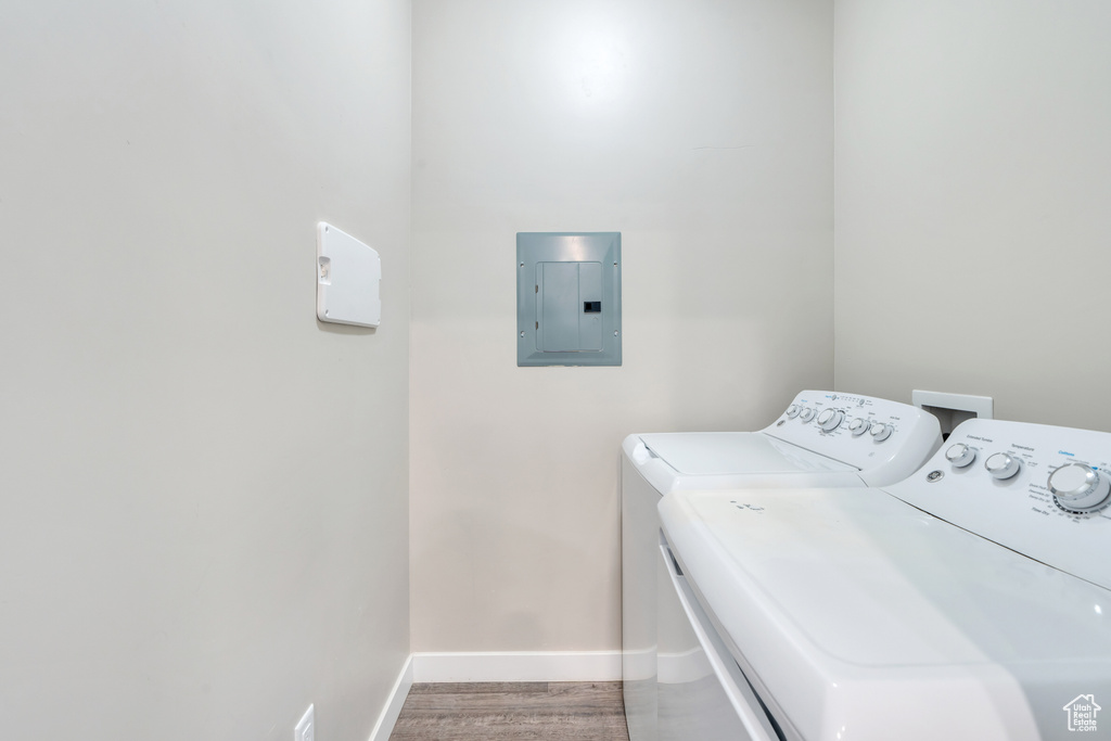 Laundry area with wood-type flooring, separate washer and dryer, and electric panel