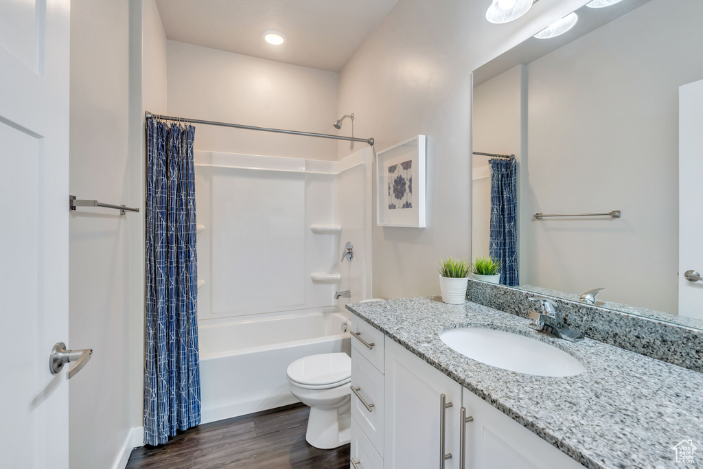 Full bathroom featuring shower / tub combo with curtain, hardwood / wood-style flooring, vanity, and toilet