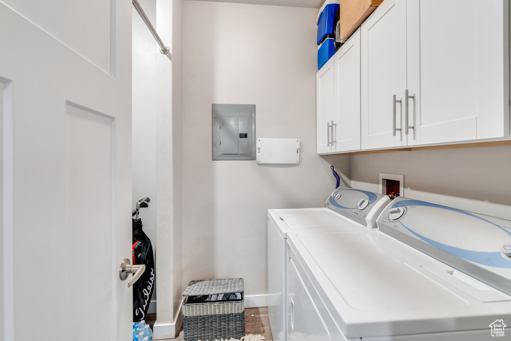 Clothes washing area with cabinets, electric panel, and independent washer and dryer