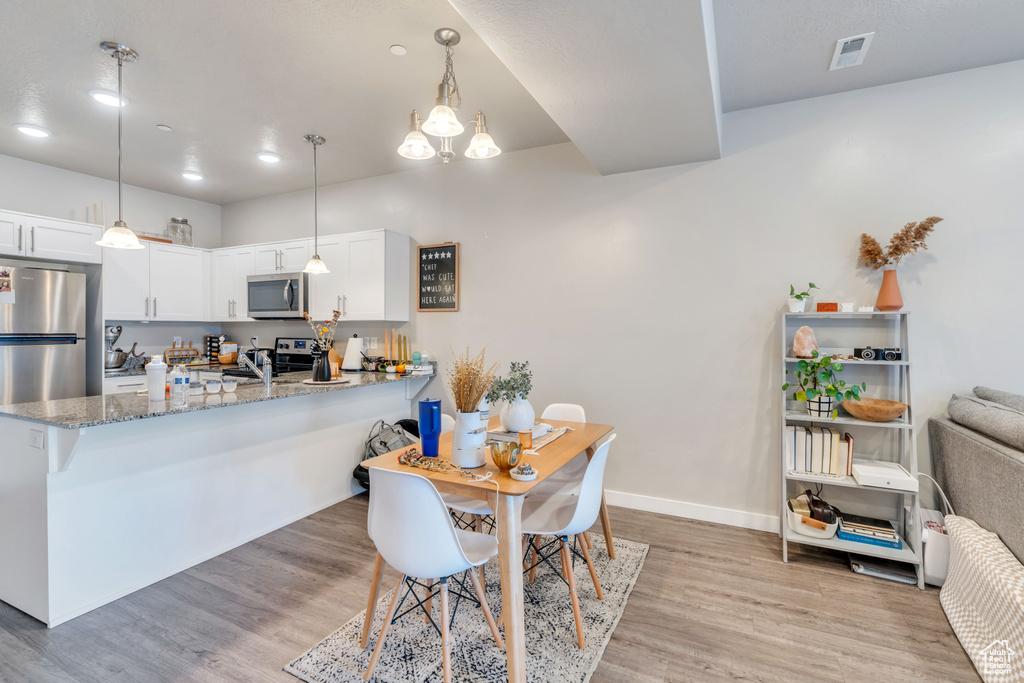 Kitchen with appliances with stainless steel finishes, kitchen peninsula, and white cabinetry