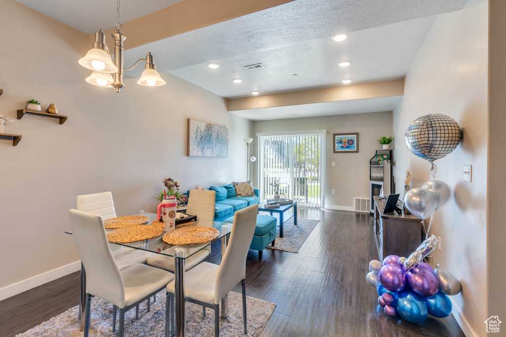 Dining space featuring a textured ceiling, an inviting chandelier, and dark hardwood / wood-style floors