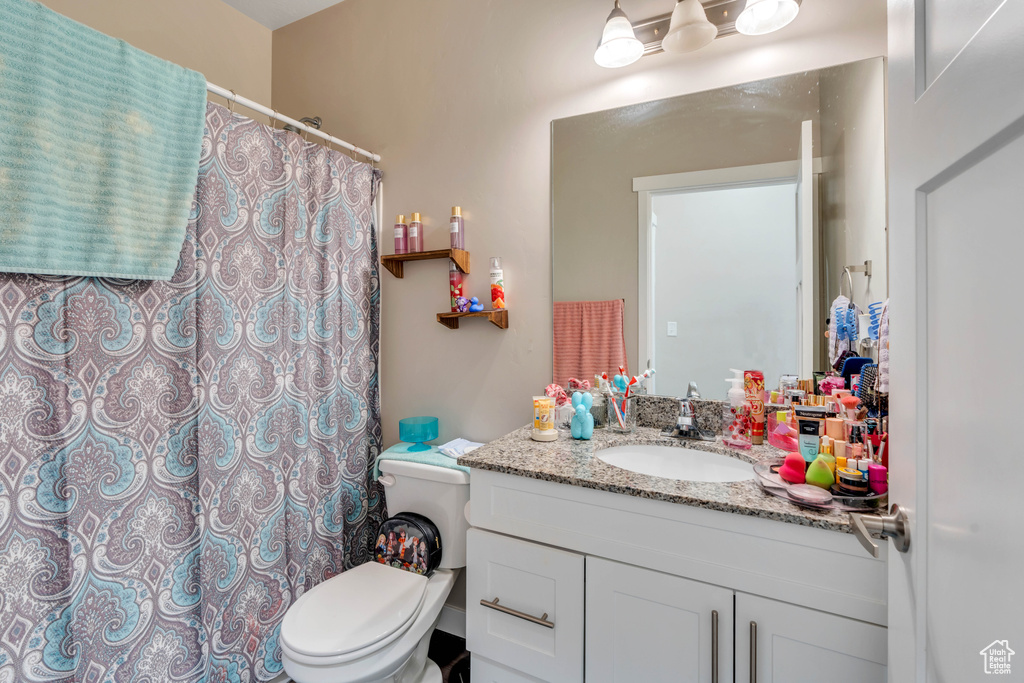 Bathroom with vanity, toilet, and a shower with shower curtain
