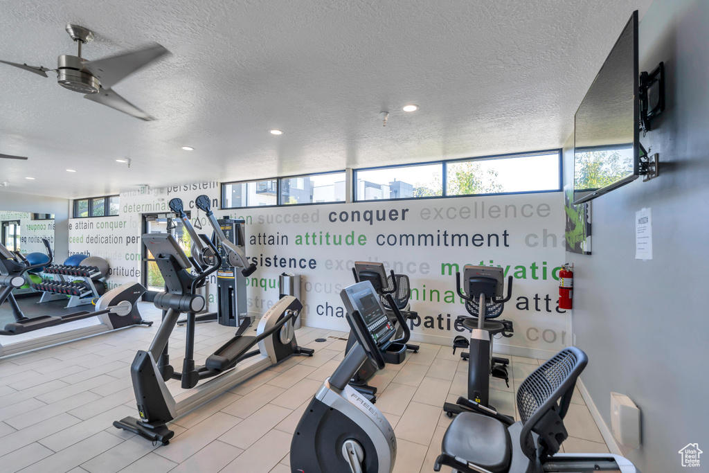 Gym with ceiling fan and a textured ceiling