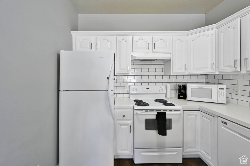 Kitchen with decorative backsplash, white appliances, and white cabinetry