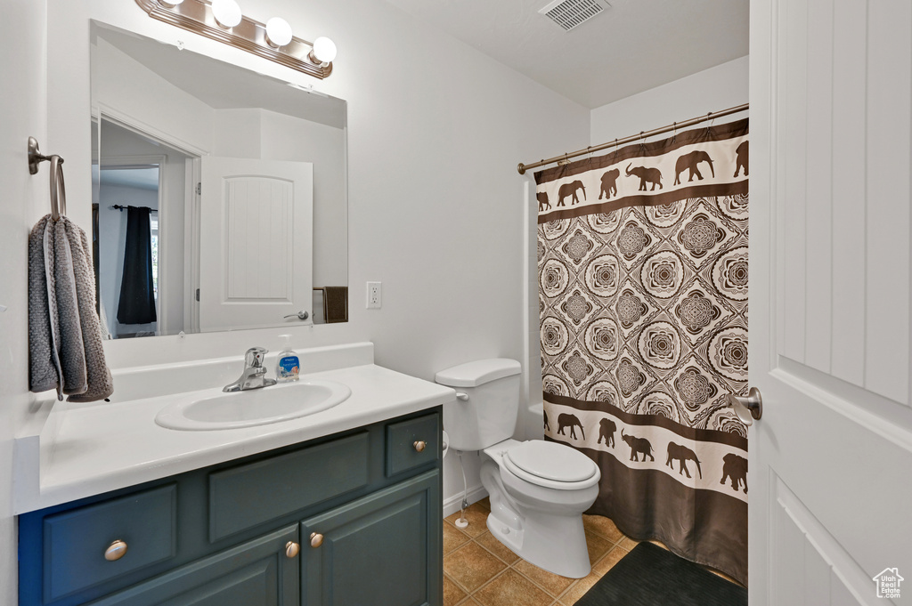 Bathroom featuring tile patterned floors, a shower with shower curtain, vanity, and toilet