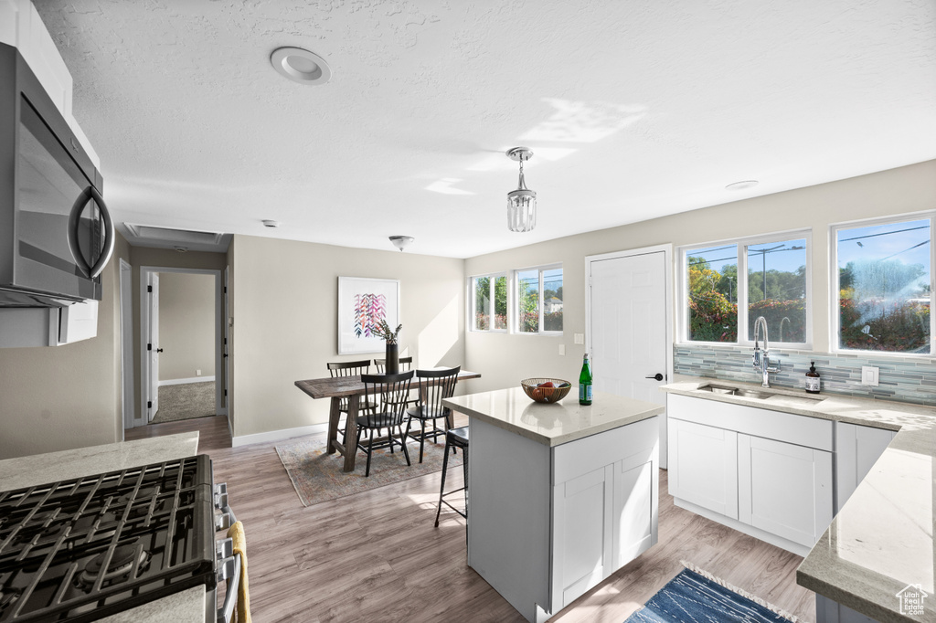 Kitchen featuring light hardwood / wood-style floors, a center island, stainless steel appliances, and white cabinets