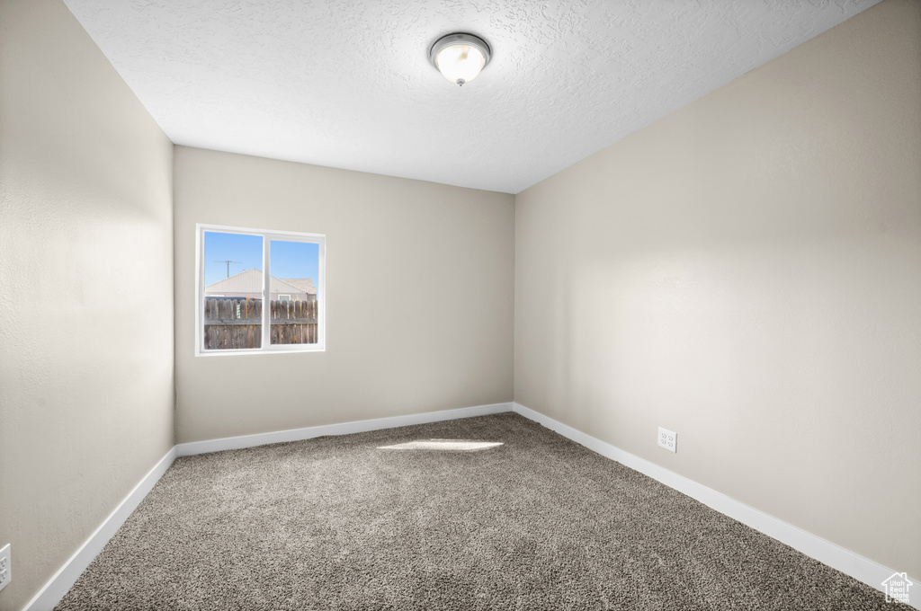 Carpeted spare room with a textured ceiling