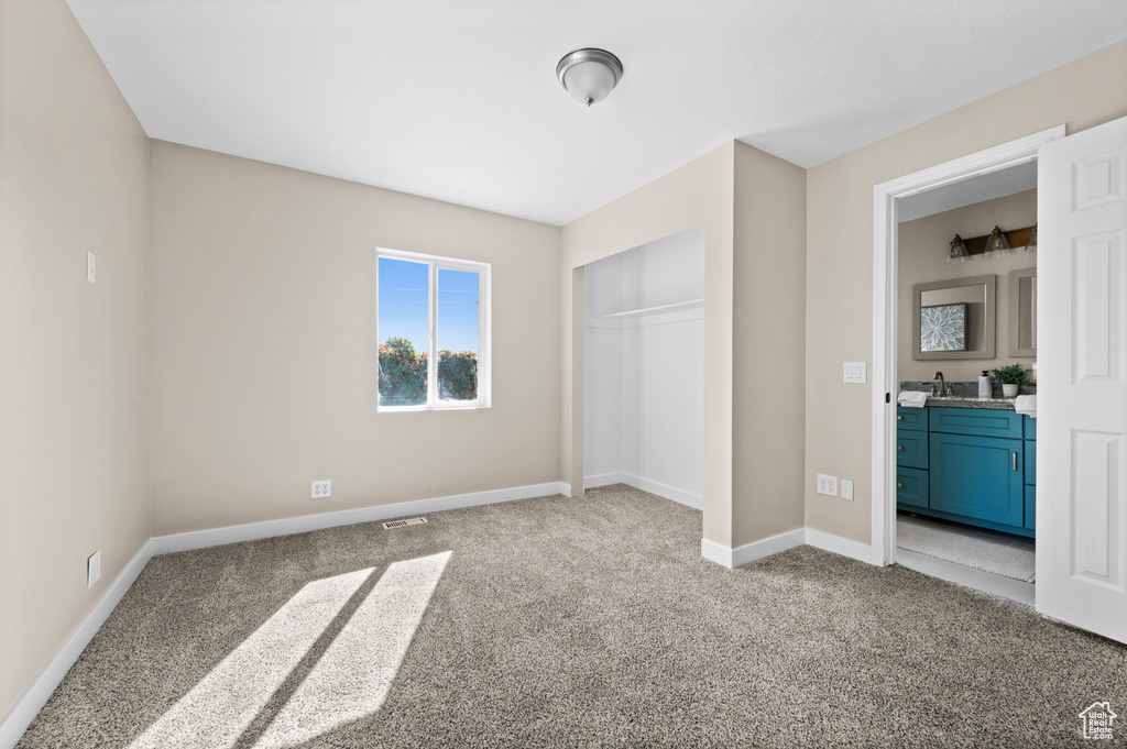 Unfurnished bedroom with light colored carpet, a closet, and sink