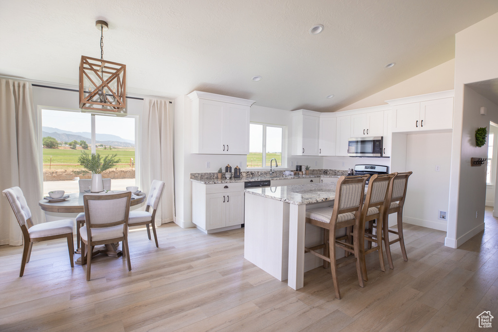 Kitchen with white cabinets, a mountain view, light wood-type flooring, lofted ceiling, and a center island