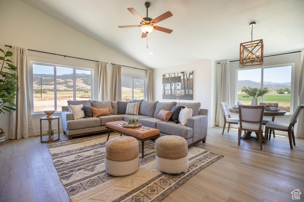 Living room featuring ceiling fan with notable chandelier, light hardwood / wood-style flooring, a mountain view, and plenty of natural light