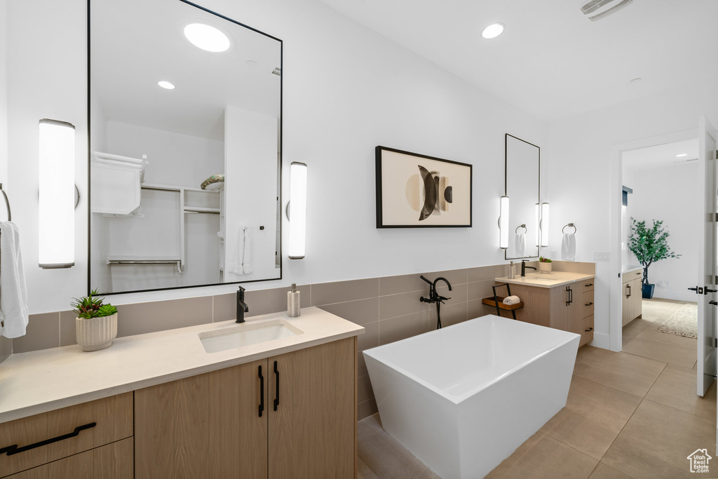 Bathroom featuring vanity, a bathtub, tile patterned flooring, and tile walls