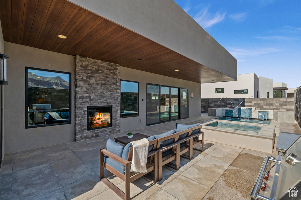 View of patio / terrace featuring a pool with hot tub, an outdoor stone fireplace, and pool water feature