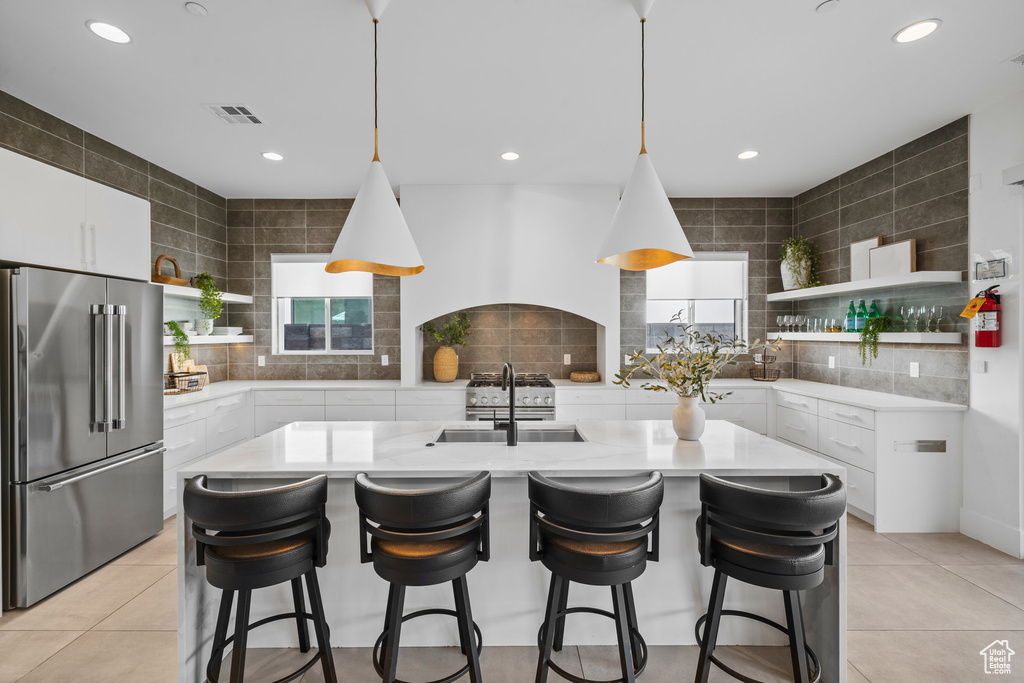 Kitchen with white cabinets, sink, high end refrigerator, and a wealth of natural light