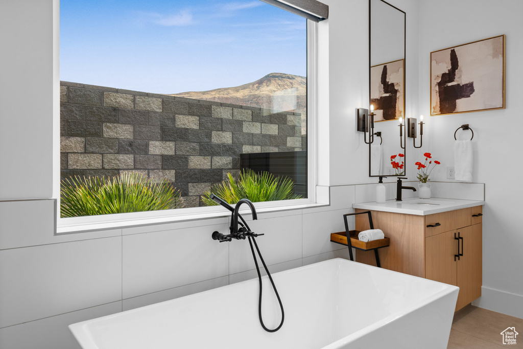 Bathroom with a tub to relax in, a mountain view, tile walls, and vanity