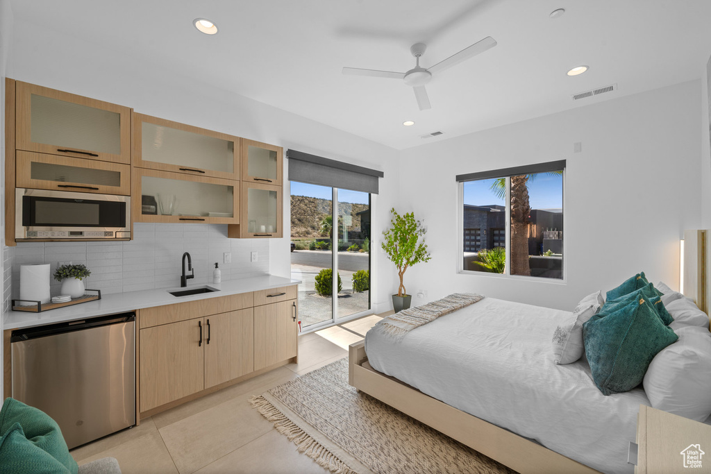 Tiled bedroom with ceiling fan, sink, access to exterior, and multiple windows