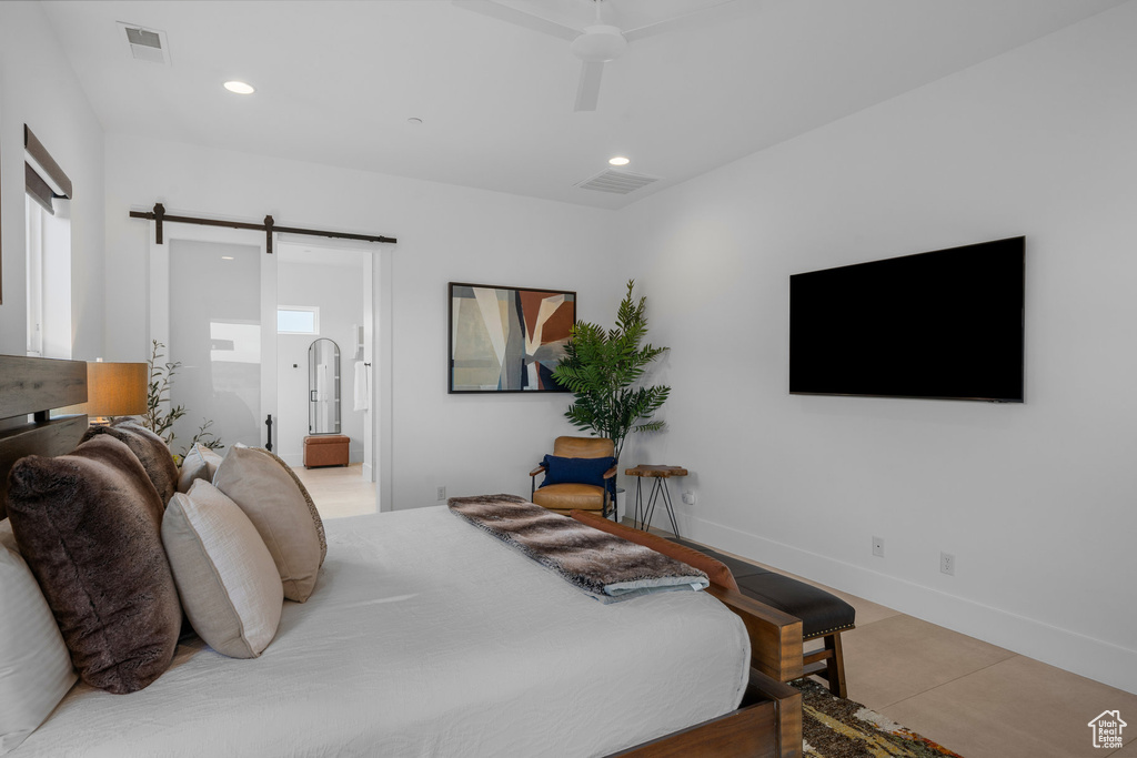 Bedroom with ceiling fan, light tile patterned floors, and a barn door