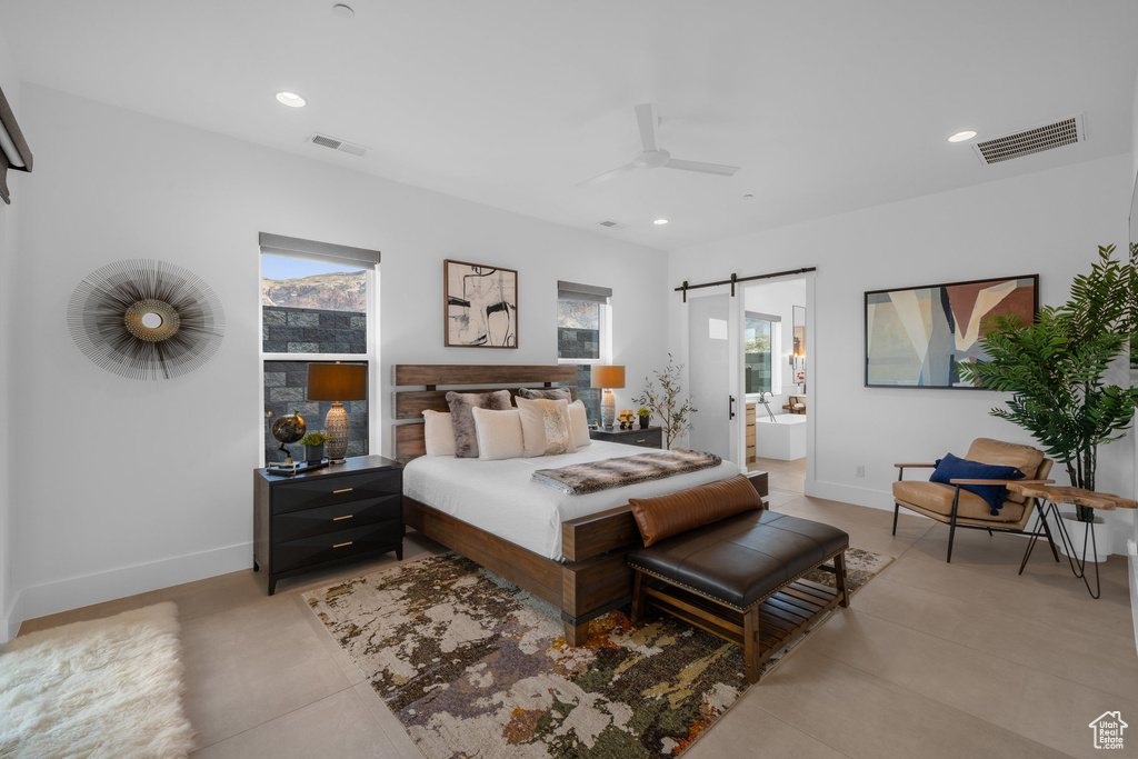 Bedroom with ensuite bath, ceiling fan, and a barn door