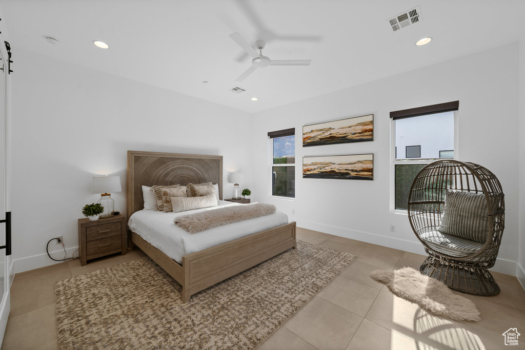 Bedroom featuring light tile patterned flooring, ceiling fan, and a barn door