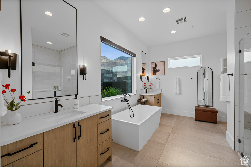 Bathroom featuring shower with separate bathtub, tile patterned floors, vanity, and a healthy amount of sunlight