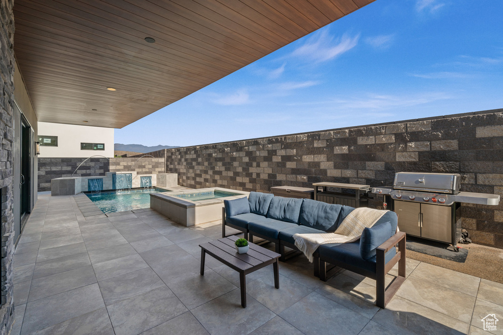 View of patio / terrace with outdoor lounge area, a mountain view, a swimming pool with hot tub, grilling area, and pool water feature