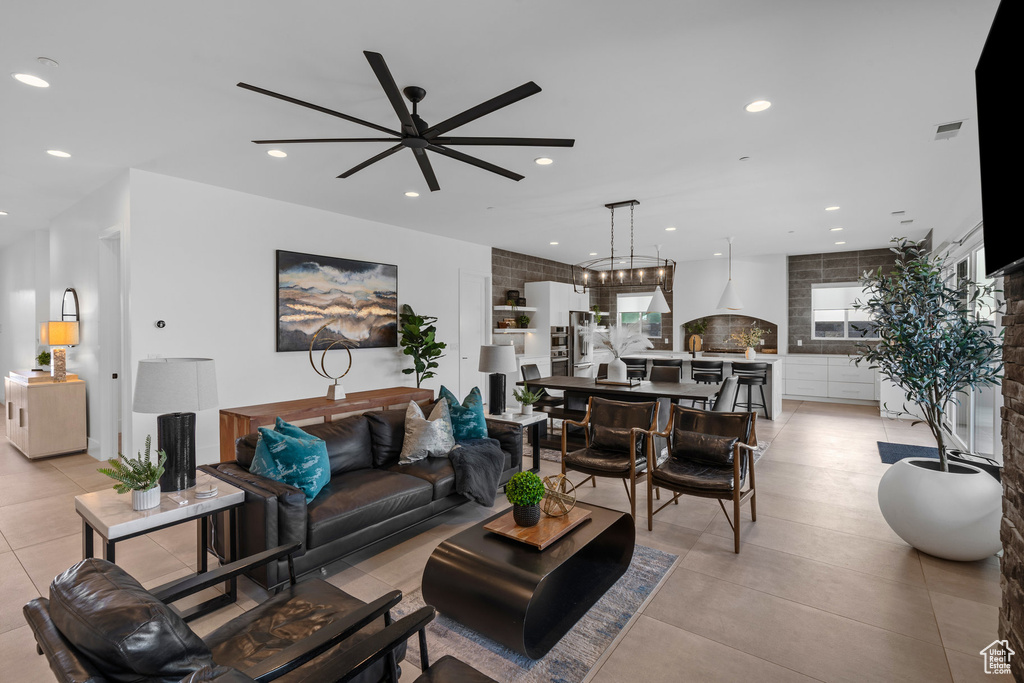 Tiled living room with ceiling fan with notable chandelier