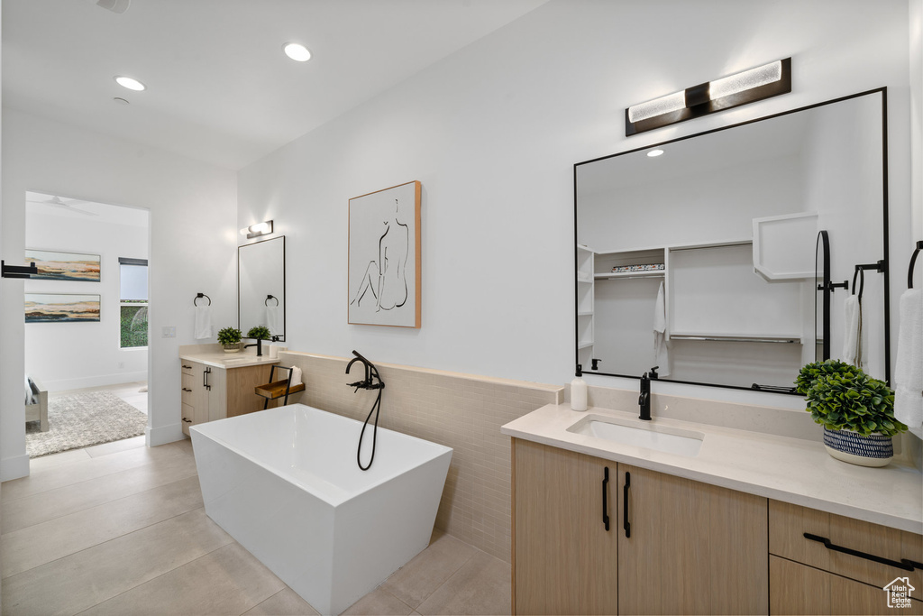 Bathroom featuring vanity, tile patterned flooring, and a tub