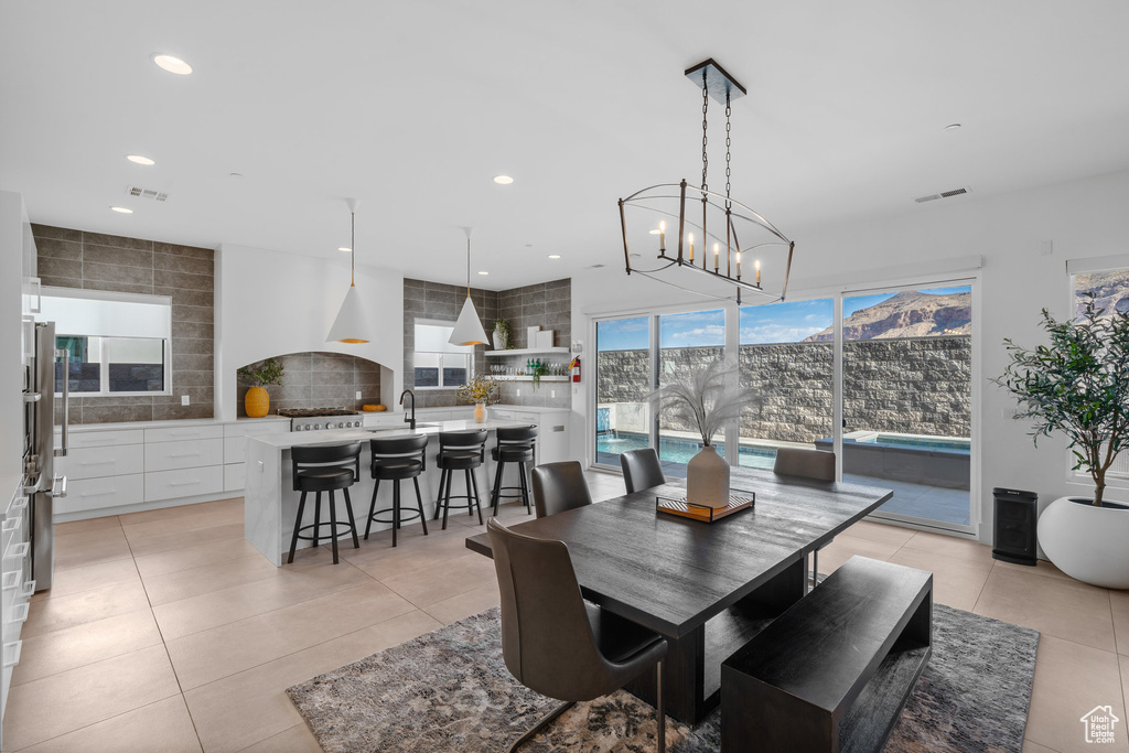 Dining room with light tile patterned flooring, plenty of natural light, sink, and a notable chandelier