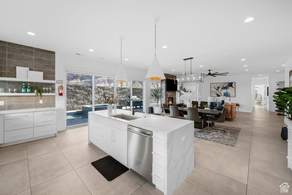 Kitchen featuring a kitchen island with sink, pendant lighting, sink, white cabinets, and stainless steel dishwasher