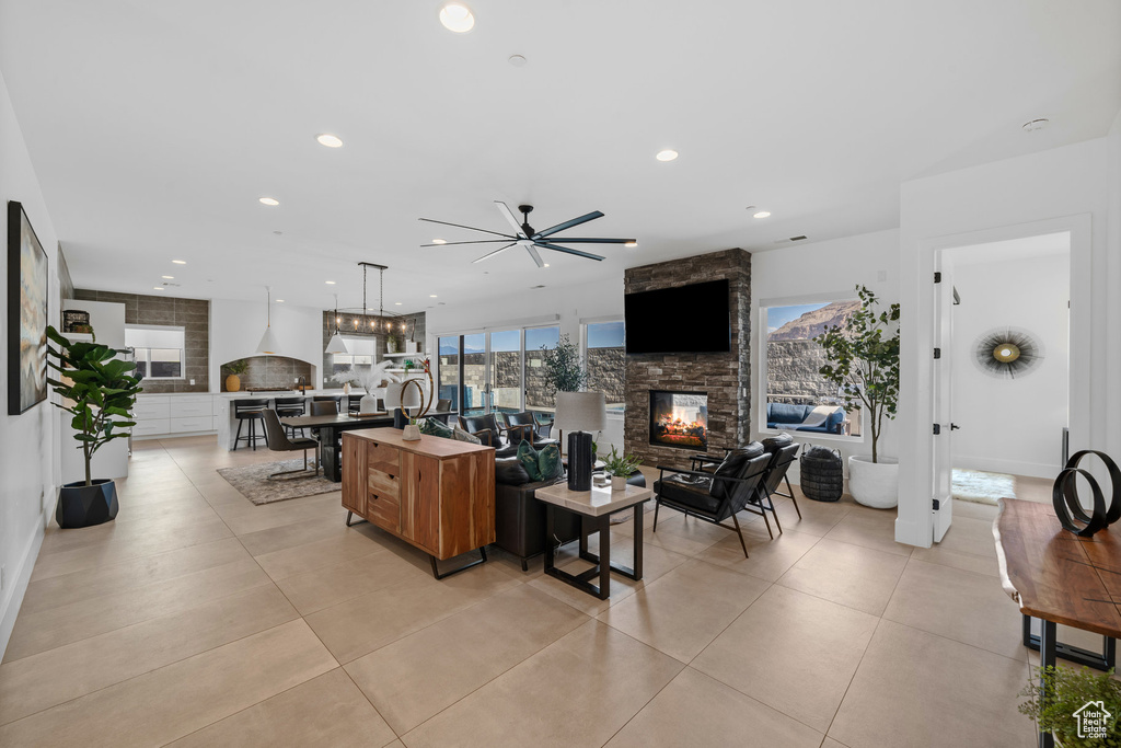 Living room with ceiling fan, a stone fireplace, and light tile patterned floors